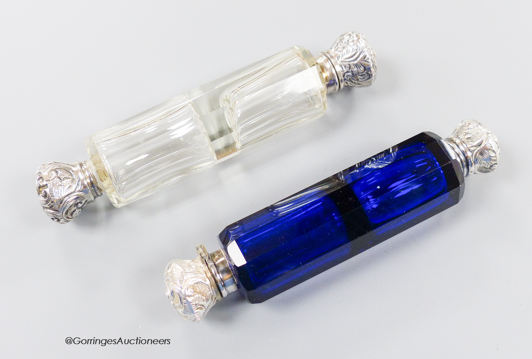 A late Victorian white metal mounted decagonal blue glass double ended scent bottle, 12.3cm (chip) and one other similar mounted clear glass scent bottle.